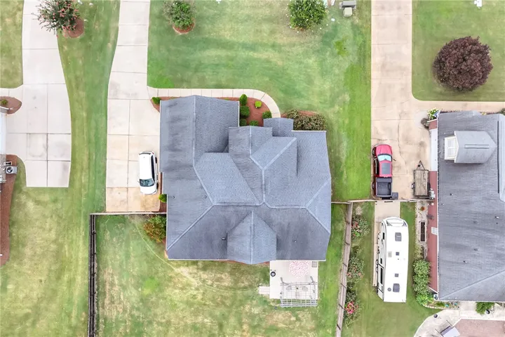 An aerial perspective showcases a well-maintained home with a sizable yard and a paved driveway.