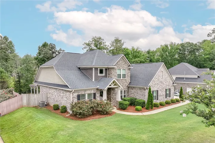 A classic brick and stone residence, framed by mature trees, boasts a neatly landscaped front yard.