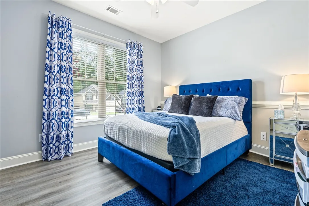 Hardwood-style flooring extends across this naturally illuminated bedroom, offering a serene and inviting atmosphere.