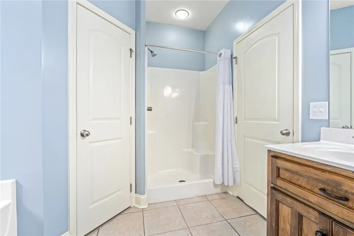 Well-appointed bathroom features a shower and a wood vanity with a white countertop.