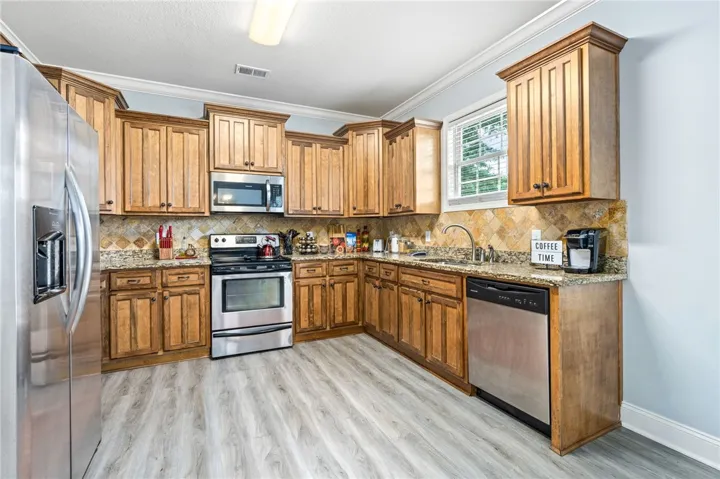 A well-appointed kitchen features ample cabinetry, granite counters, and modern stainless steel appliances.