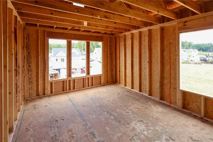 Exposed wood framing and subflooring define this room under construction with views of the neighborhood.