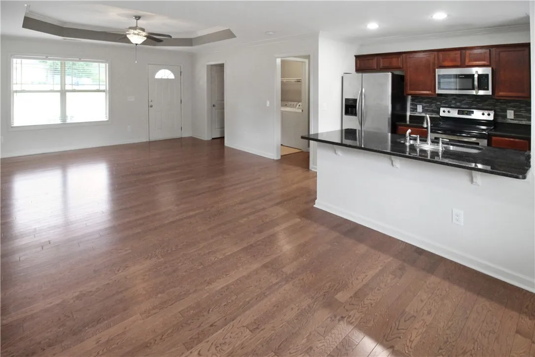 Hardwood floors stretch across this open-concept layout, connecting the living area to a modern kitchen.