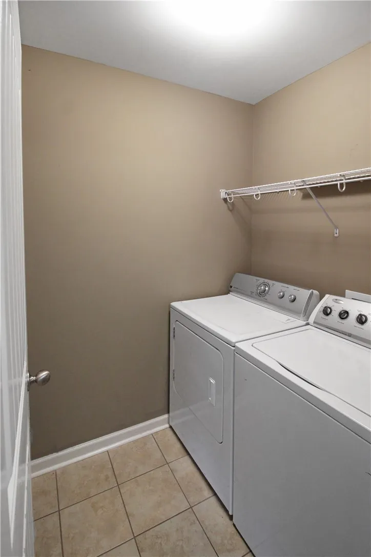 Functional laundry space featuring a practical wire shelf and tile flooring.