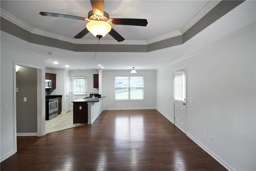 Hardwood flooring extends throughout this generous living space, connecting to a modern kitchen with a breakfast bar.