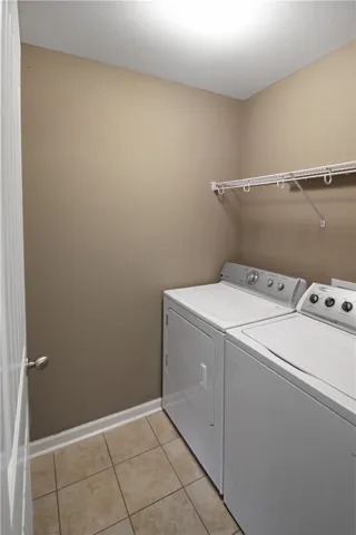 Functional laundry space featuring a practical wire shelf and tile flooring.