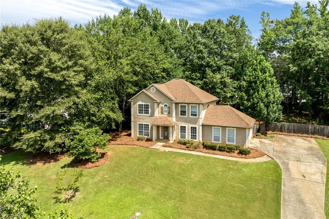 A well-maintained residence sits gracefully on a manicured lot, framed by mature, verdant trees.