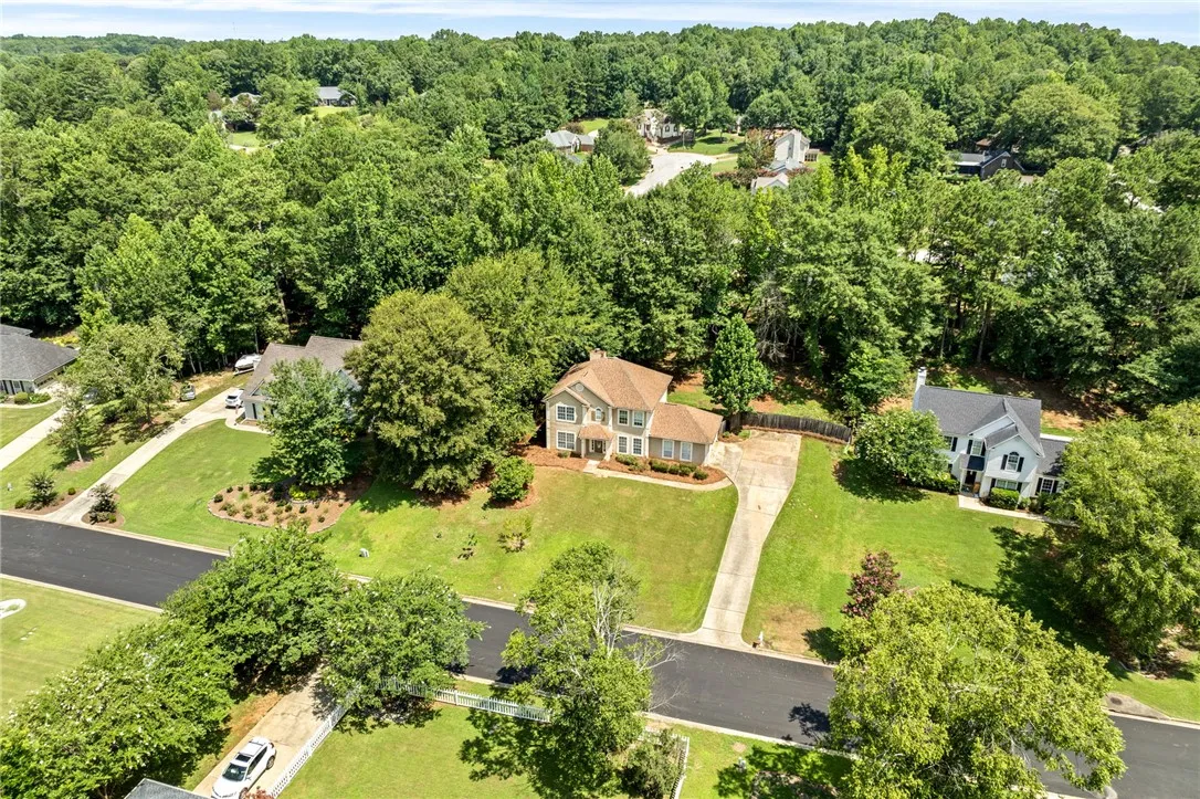 An aerial perspective reveals a charming residential property nestled amidst lush, mature trees, offering a private setting.