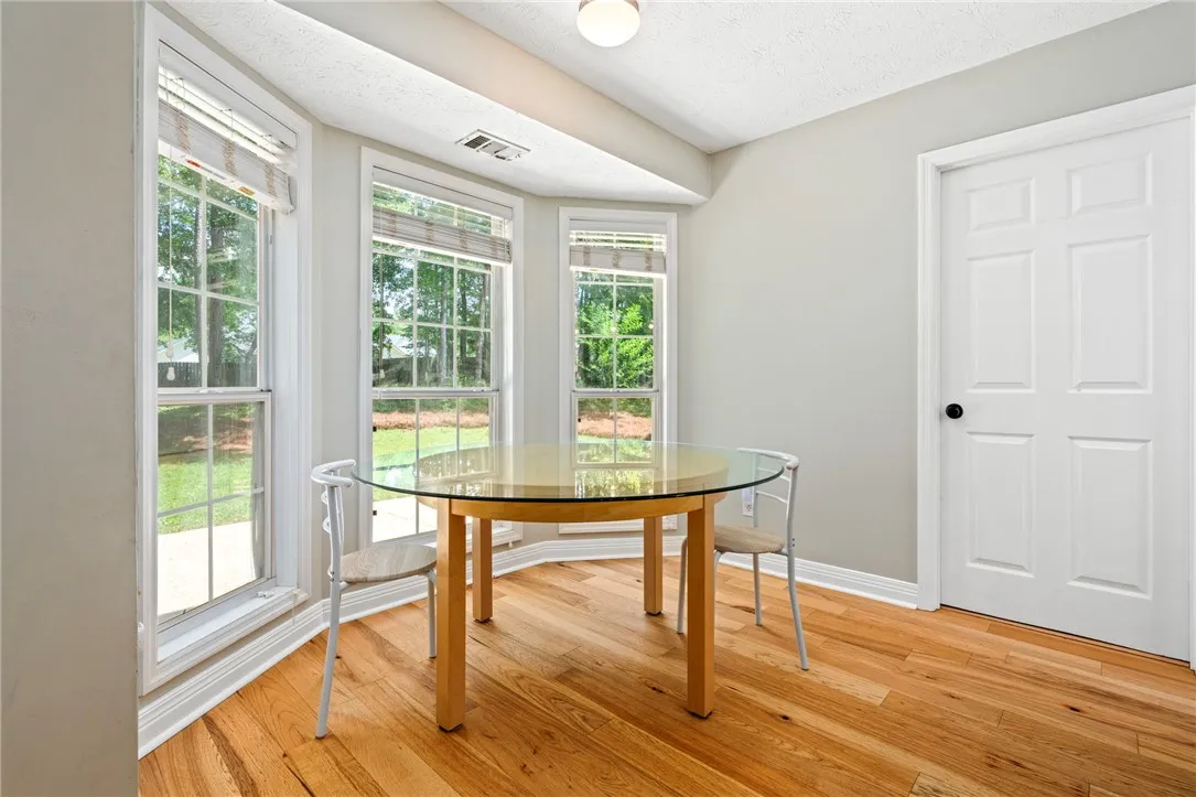 A well-lit breakfast nook offers scenic views through multiple windows, complemented by bright hardwood flooring.