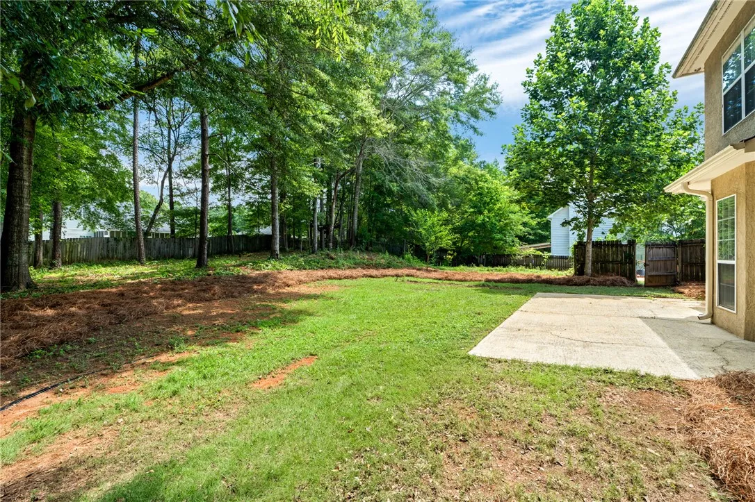 A spacious backyard with mature trees and a fresh patio offers ample outdoor living potential.