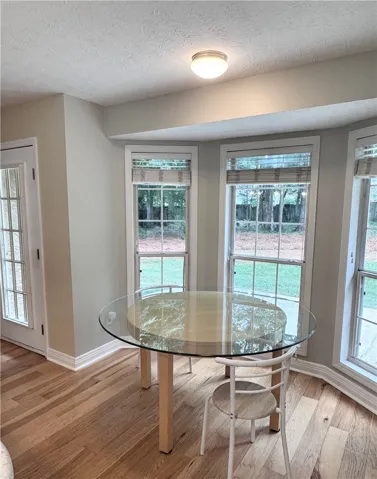 A charming breakfast nook features rich hardwood flooring and a trio of bay windows overlooking the yard.
