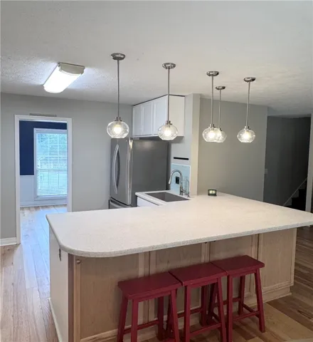 A well-lit kitchen with a spacious island, pendant lights, and hardwood flooring.