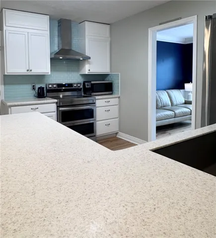 A well-appointed kitchen features stainless steel appliances and ample counter space, connecting seamlessly to a neighboring room.
