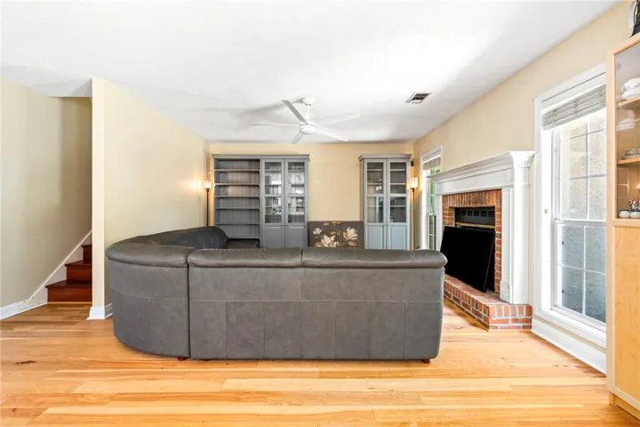 Hardwood floors stretch across this living space, featuring a brick fireplace and adjacent built-in shelving.
