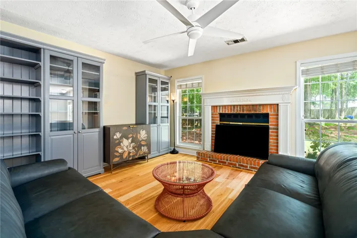 Bright hardwood floors complement the cozy brick fireplace and built-in shelving, creating a welcoming living space.