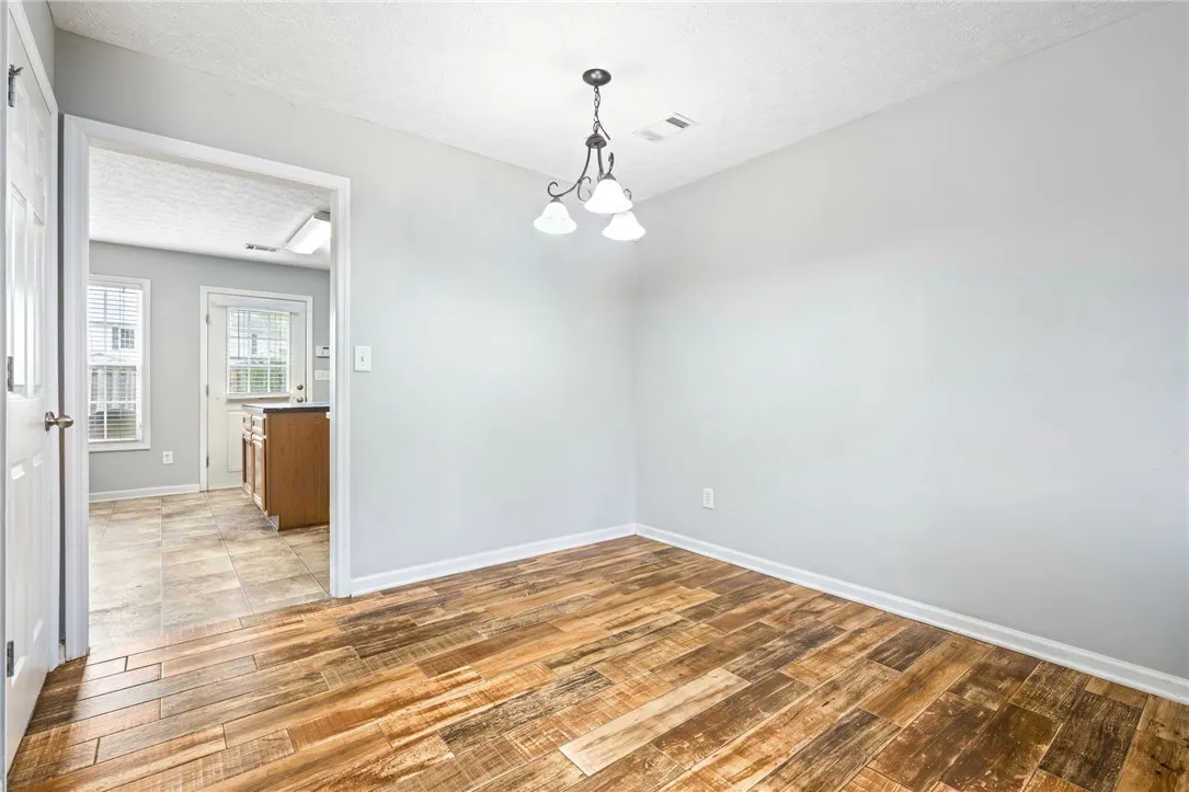 A refined dining space features LVT flooring and an elegant chandelier, perfect for intimate gatherings.