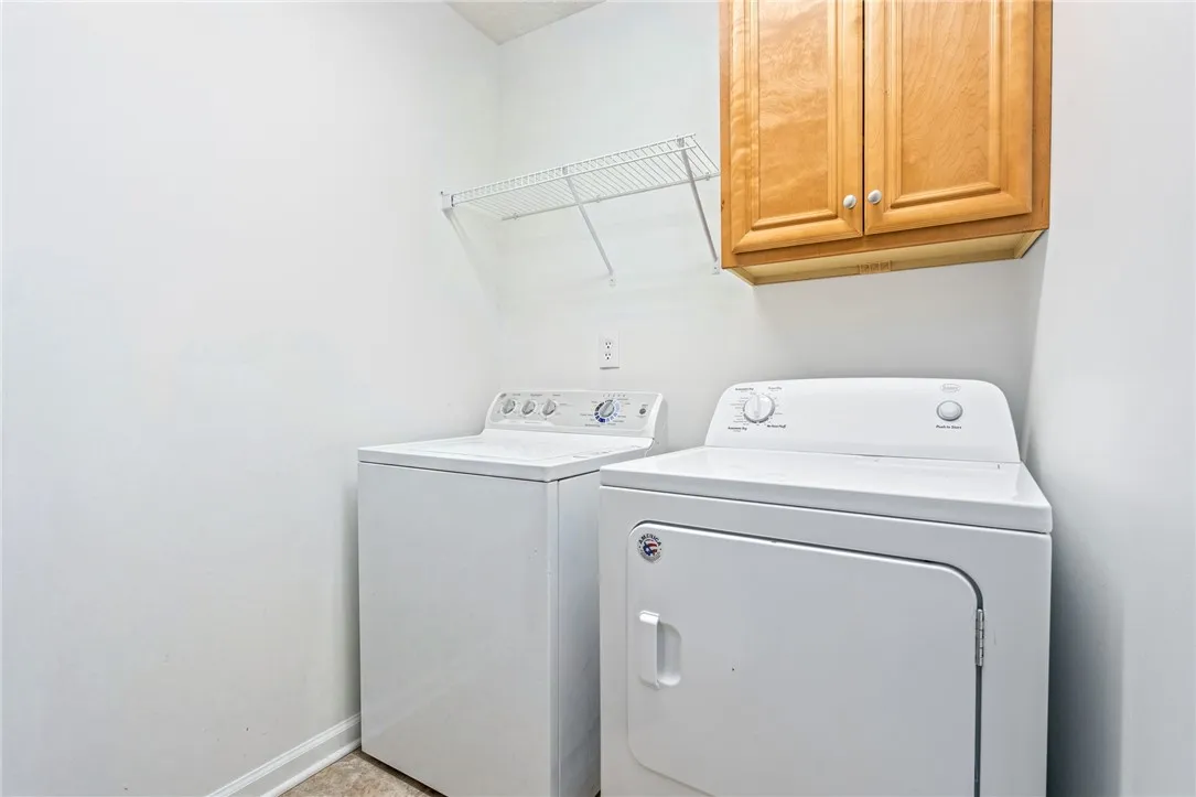Functional laundry space featuring a washer and dryer beneath a practical wall cabinet and wire shelving.