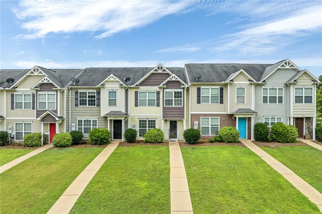 A row of modern townhouses presents welcoming entryways and well-maintained green lawns.