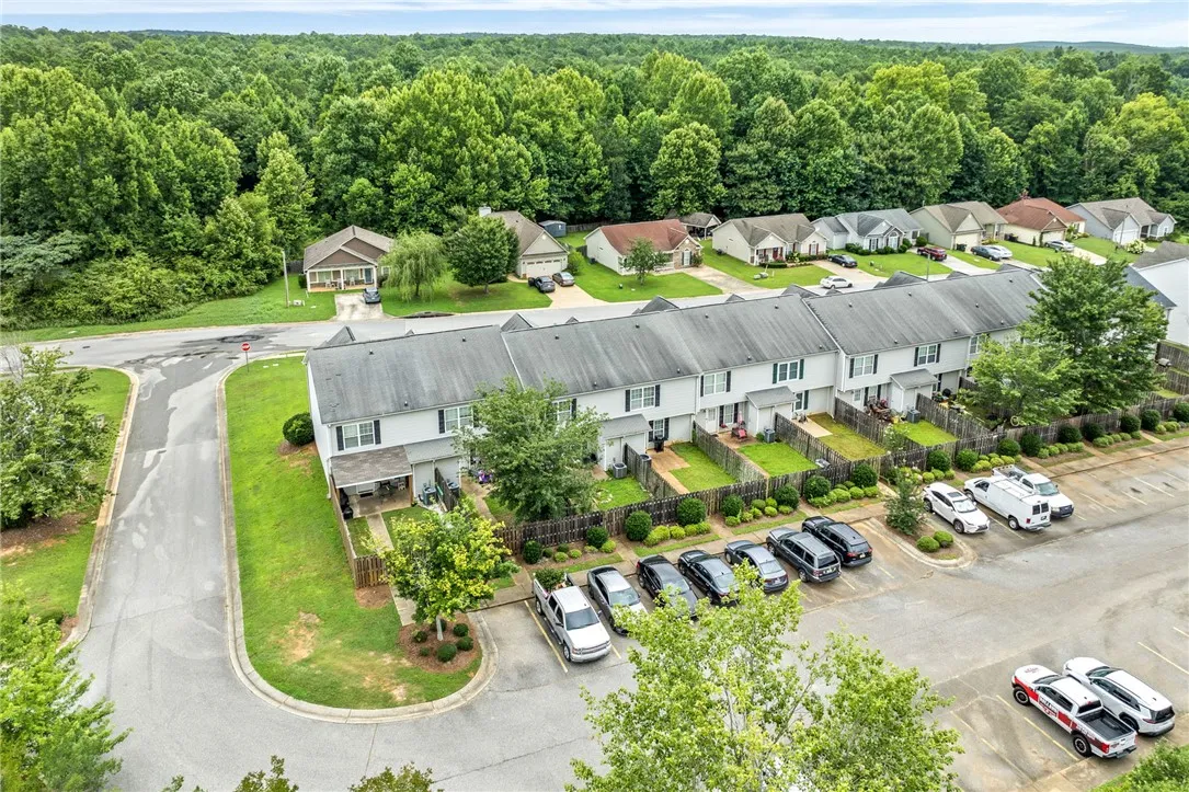 An aerial perspective reveals a cohesive neighborhood layout, featuring a row of townhomes alongside single-family residences, all nestled amongst verdant trees.