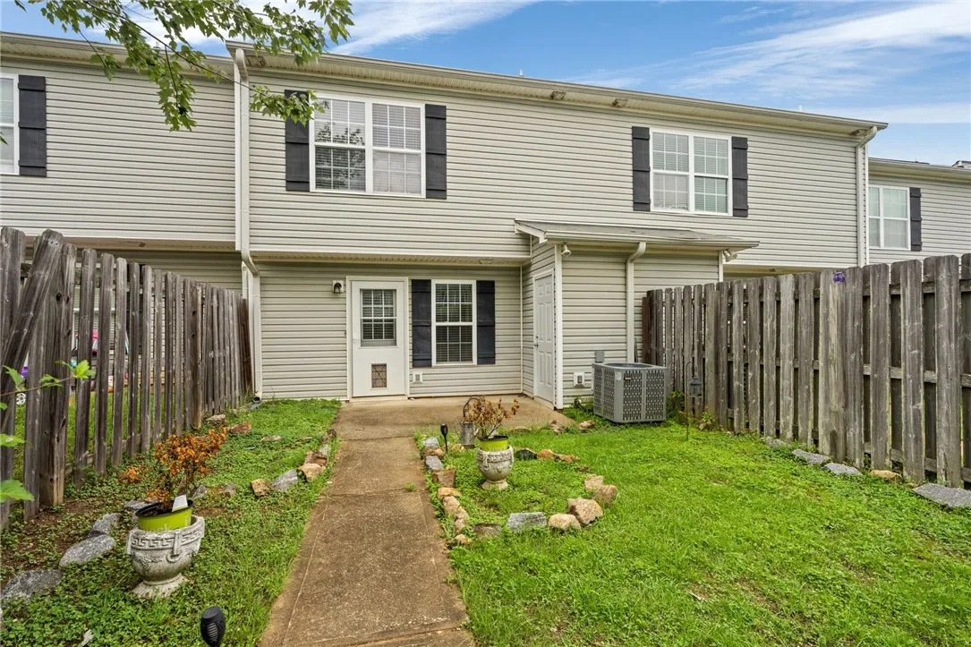 A private, fenced backyard offers a concrete path and garden space.