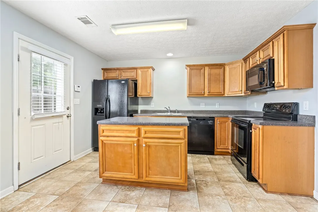 A well-appointed kitchen features a central island, black appliances, and ample cabinetry for culinary pursuits.