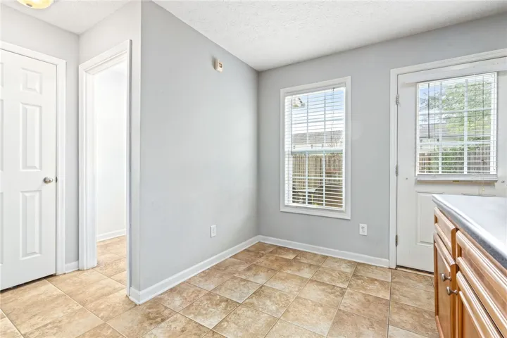 A well-lit breakfast nook with practical tile flooring and convenient exterior access.