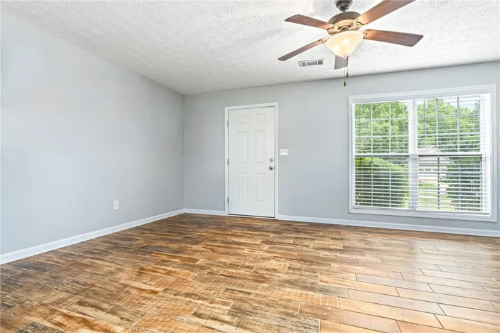 A well-lit interior space features wood-look tile flooring and a ceiling fan, offering a comfortable living area.