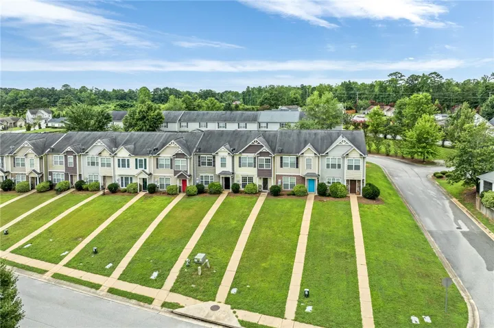 Rows of well-kept townhomes with individual green lawns offer a charming neighborhood aesthetic.