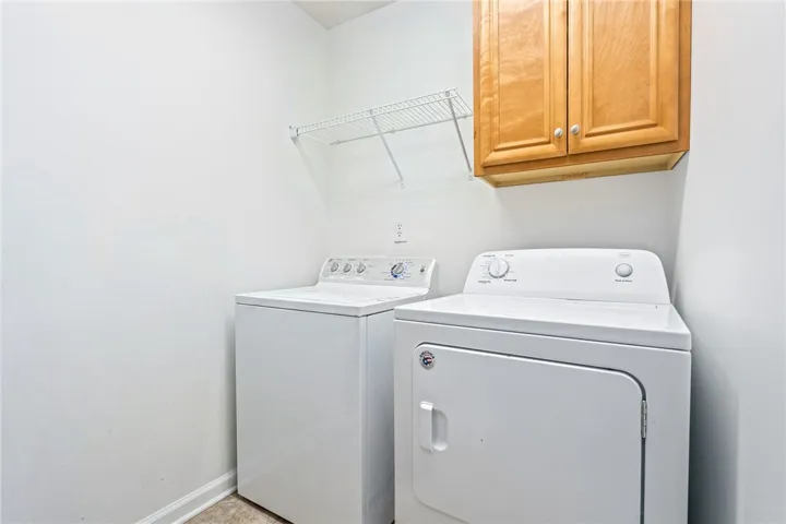 Functional laundry space featuring a washer and dryer beneath a practical wall cabinet and wire shelving.