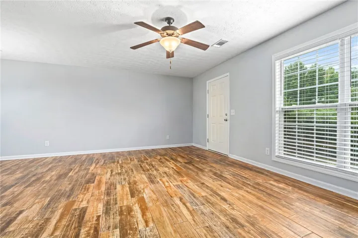 A versatile living area features durable LVT flooring, ample natural light, and a ceiling fan for comfort.