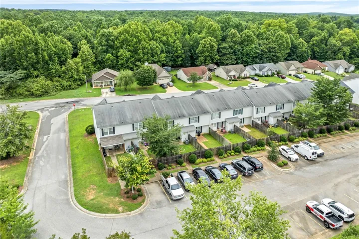 An aerial perspective reveals a cohesive neighborhood layout, featuring a row of townhomes alongside single-family residences, all nestled amongst verdant trees.