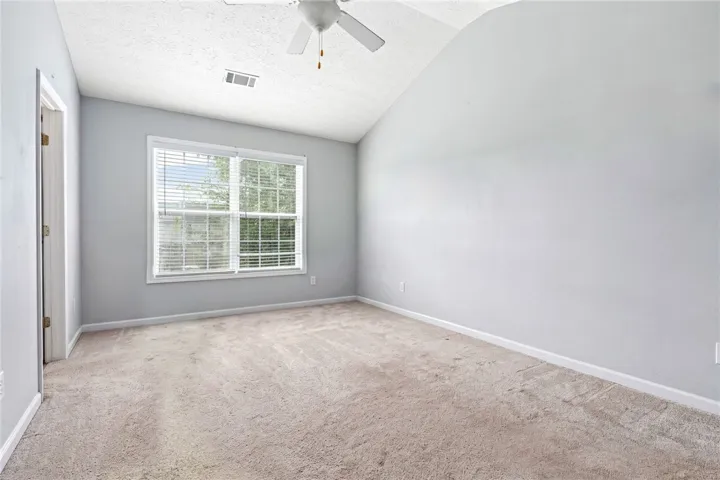 A comfortable bedroom featuring a sloped ceiling and a broad window.