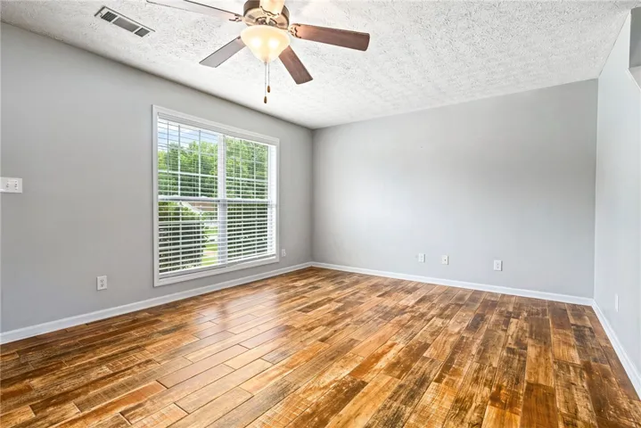 A well-lit room showcases rich LVT flooring and a refreshing ceiling fan.