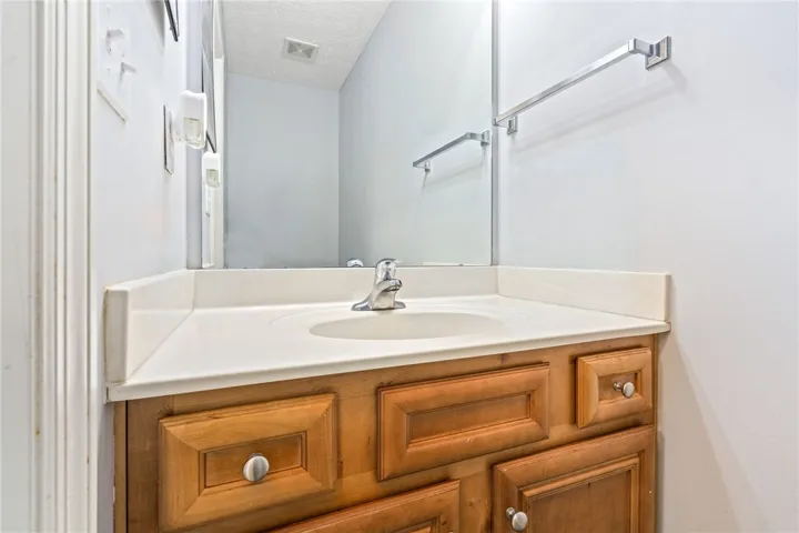 A well-lit vanity with a neutral countertop and wooden cabinetry offers functional elegance to this essential space.
