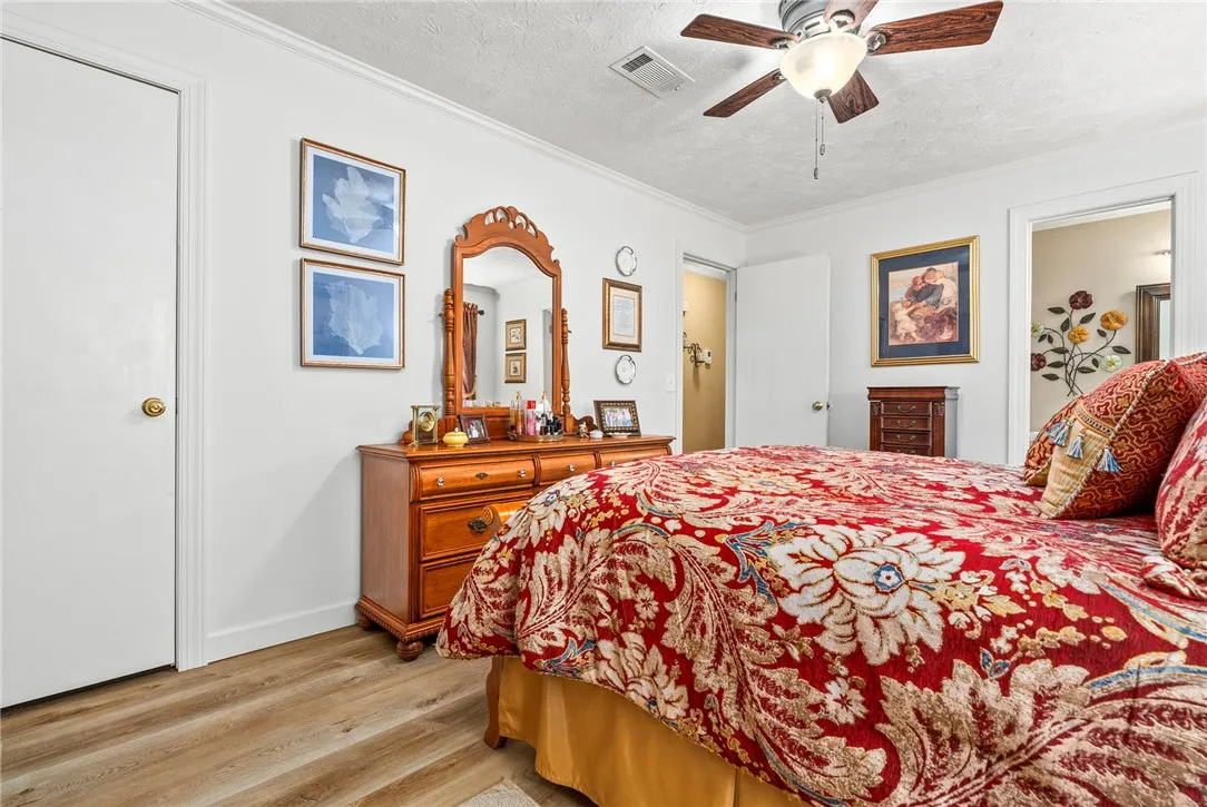 Comfortable bedroom with warm flooring and a cooling ceiling fan for relaxation.