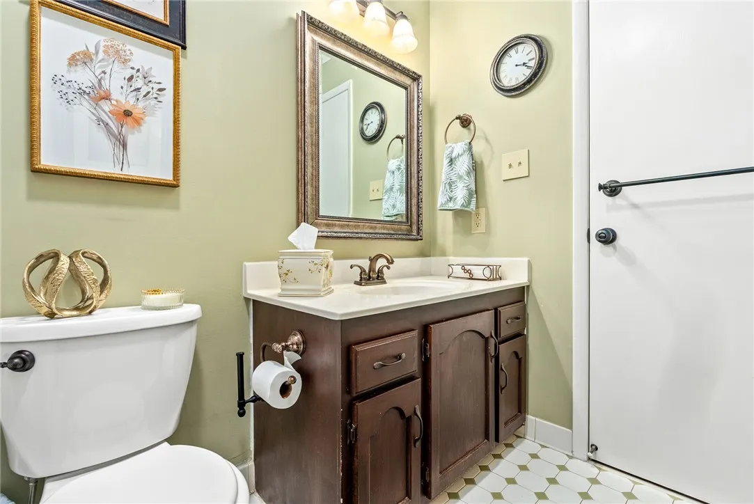 A well-lit bathroom features a vanity with ample storage and classic tiled flooring.