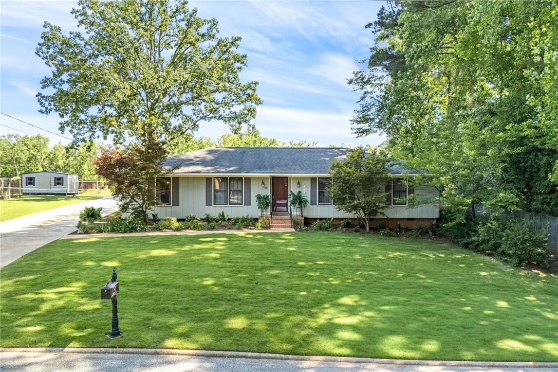Mature trees frame this charming residence, boasting a well-manicured lawn and a welcoming facade.
