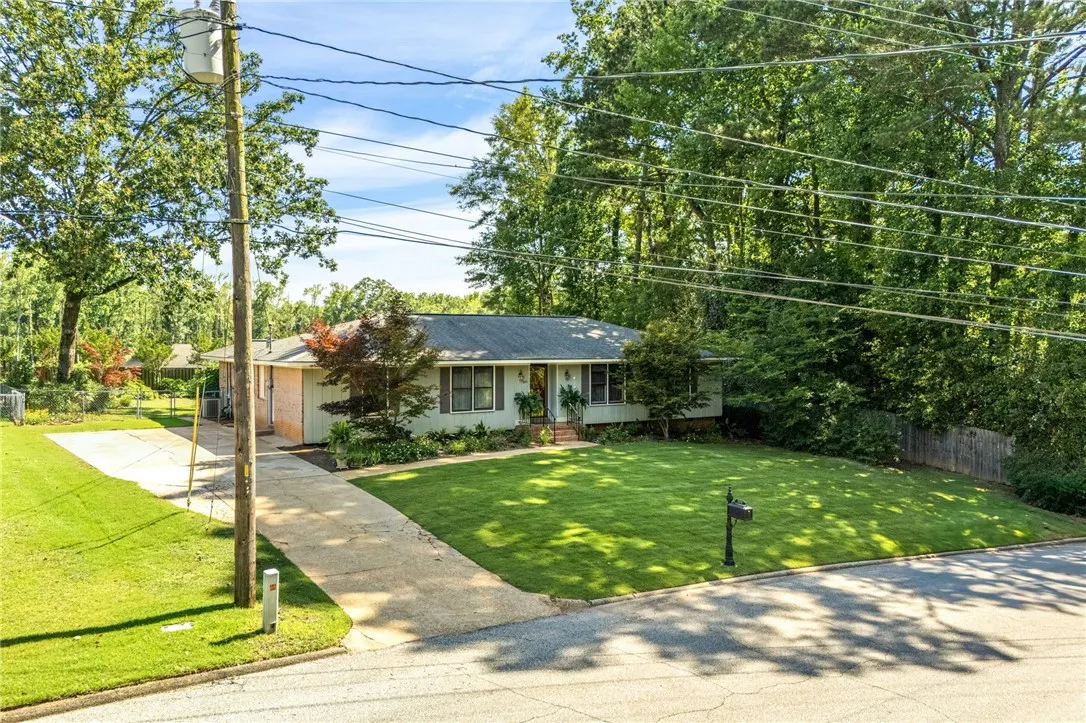 A well-maintained ranch home with a verdant lawn and mature trees offering peaceful privacy.