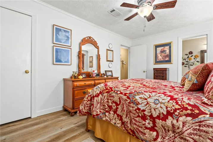 Comfortable bedroom with warm flooring and a cooling ceiling fan for relaxation.