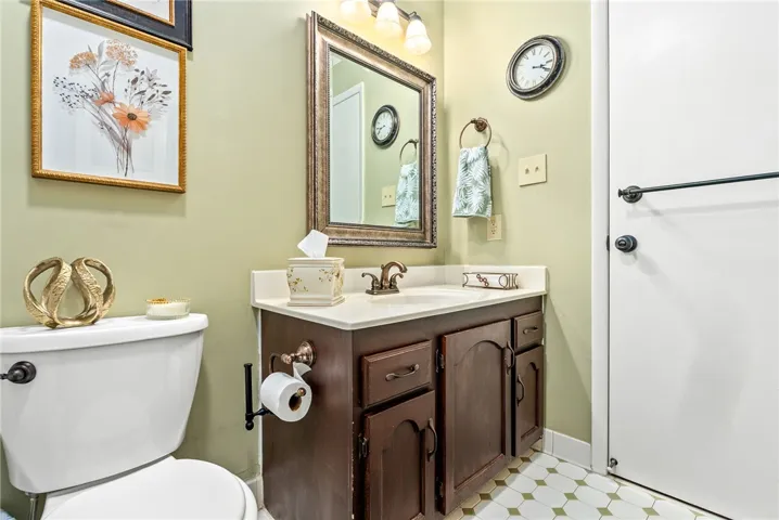 A well-lit bathroom features a vanity with ample storage and classic tiled flooring.