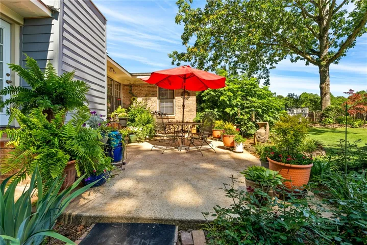 An inviting private patio awaits, surrounded by lush greenery and a manicured yard.