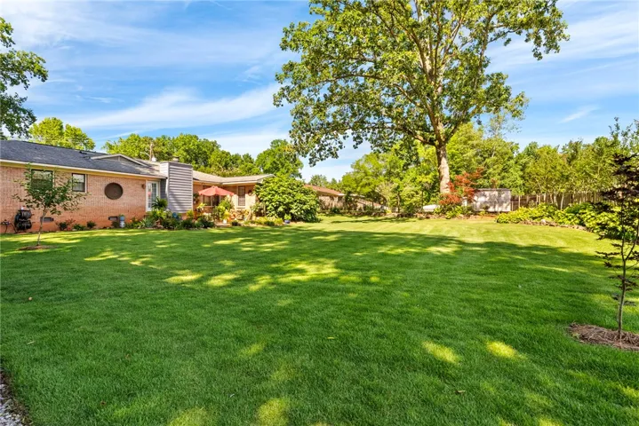An expansive backyard retreat boasts lush, well-maintained lawns and mature trees for ultimate privacy.