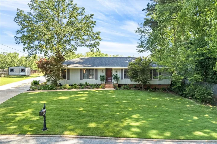 Mature trees frame this charming residence, boasting a well-manicured lawn and a welcoming facade.