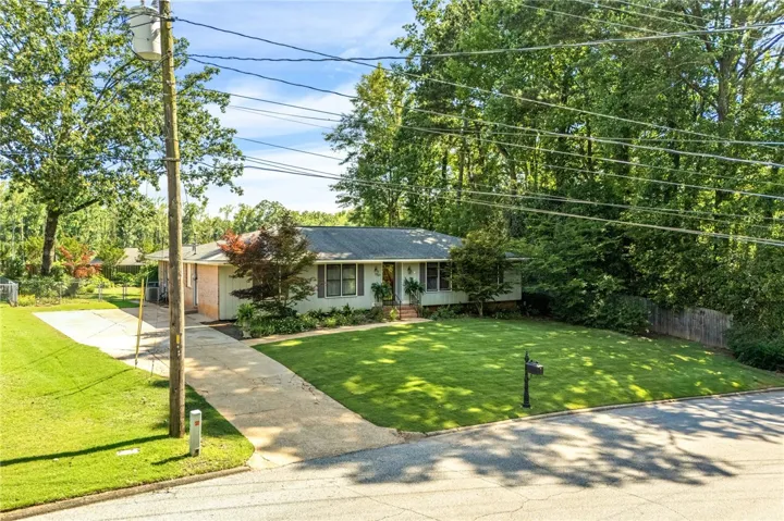 A well-maintained ranch home with a verdant lawn and mature trees offering peaceful privacy.