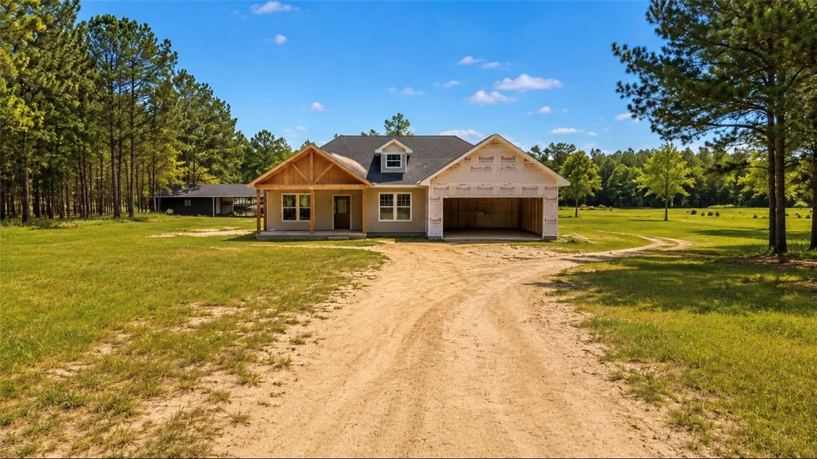 A newly constructed residence awaits customization, nestled among mature trees with a winding driveway.