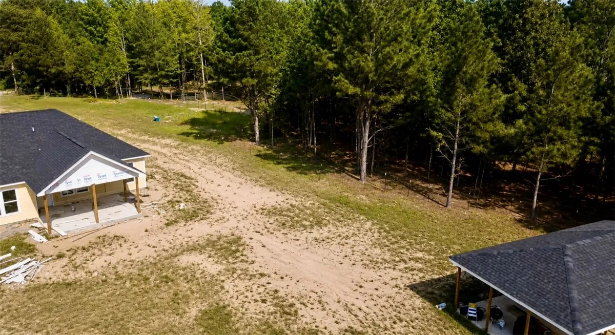 A developing property features new construction amidst a private wooded backdrop, offering ample space for outdoor pursuits.