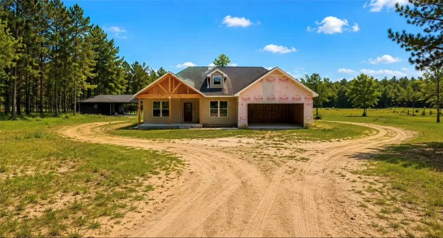 A new construction home awaits its finishing touches, nestled amidst a verdant landscape with a private drive.