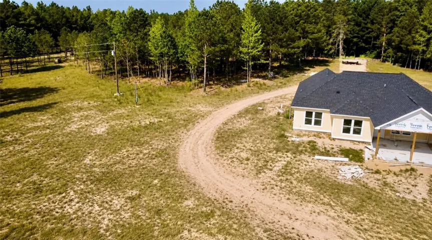 A newly constructed residence nestled on a spacious lot, surrounded by a tranquil wooded backdrop.