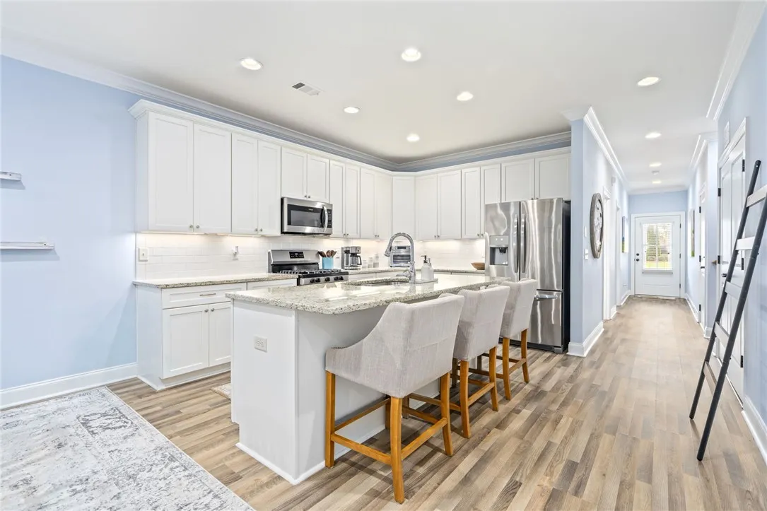 Culinary aspirations come alive in this kitchen, featuring white cabinetry and granite countertops, with ample space for dining at the island.