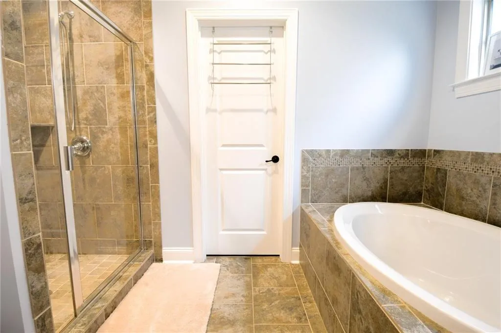 A well-appointed bathroom offers a glass-enclosed shower and a deep soaking tub, perfect for unwinding.